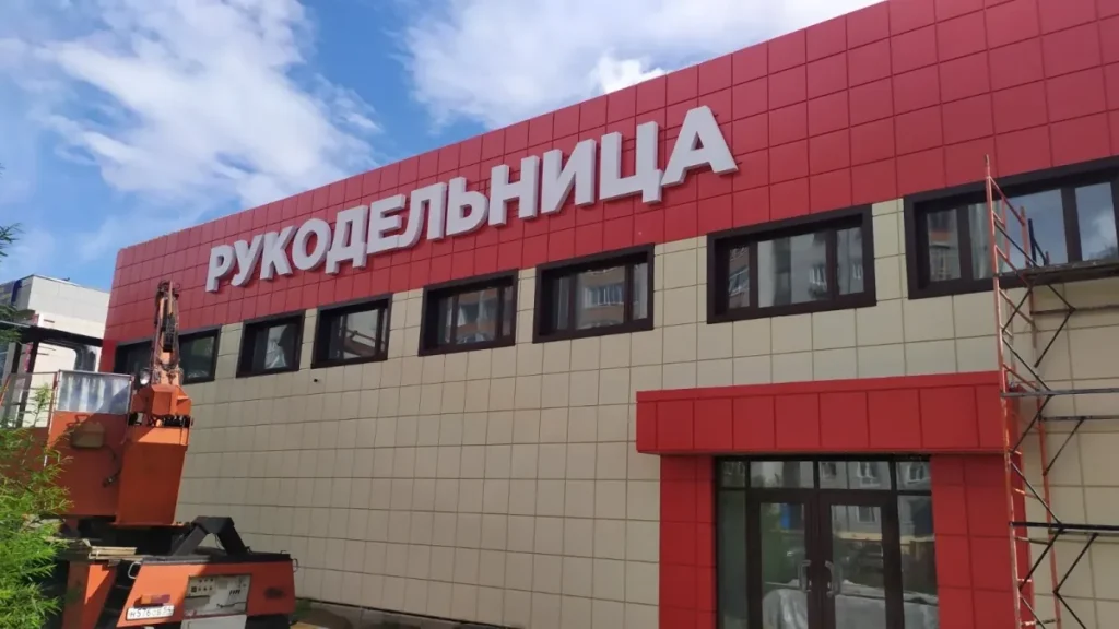 Белые буквы вывески «Рукодельница» на красной полосе фасада